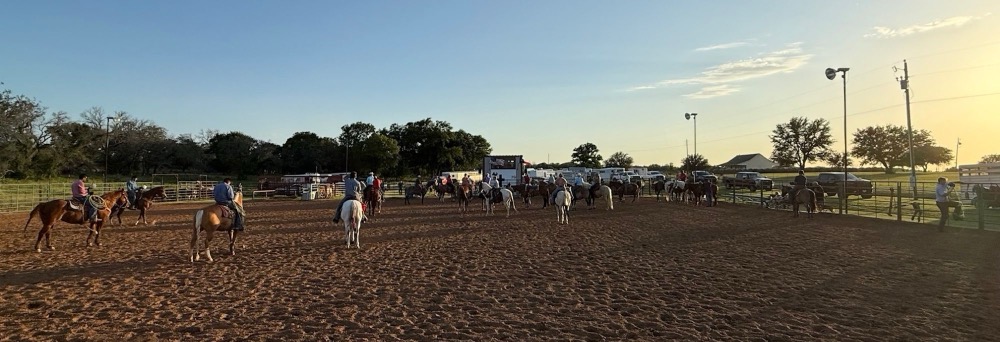 Riders gathered in the arena at Happy Trails Cowboy Church at sunset